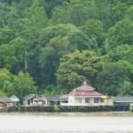 a group of houses sitting on top of a lake next to a forest